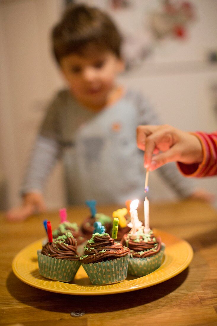 Candles being lit on birthday cupcakes