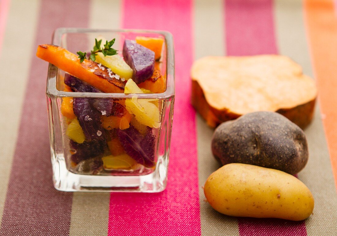 Steamed potatoes and sweet potatoes in a square glass, with raw potatoes to one side