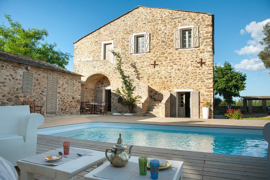 Relaxing on a shady terrace - drinks on side table in front of pool in courtyard of Mediterranean residential complex