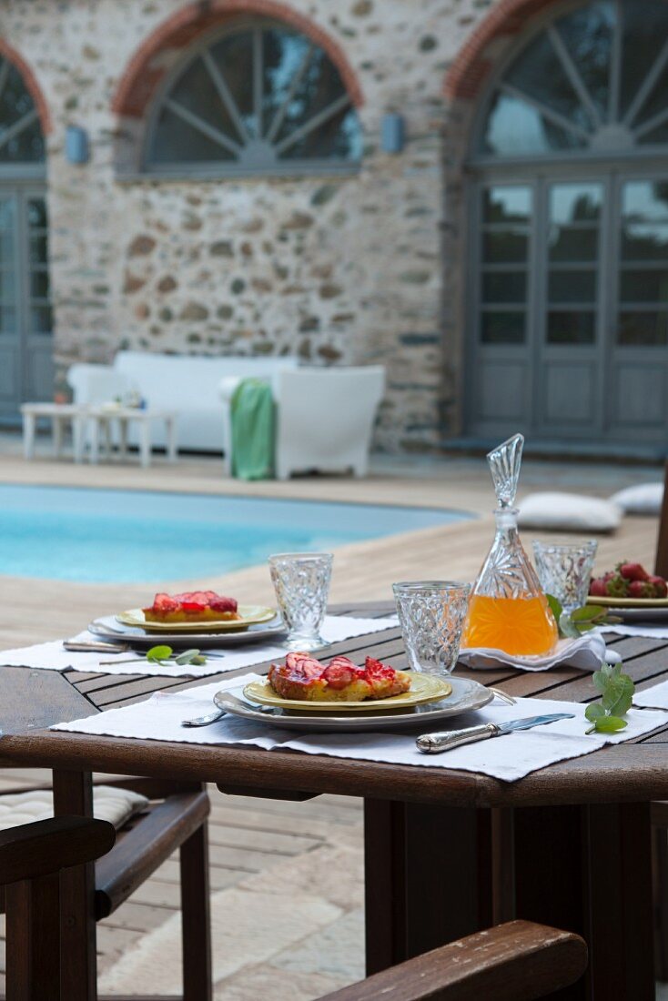 Afternoon snack on terrace table in courtyard of Mediterranean residential complex with pool