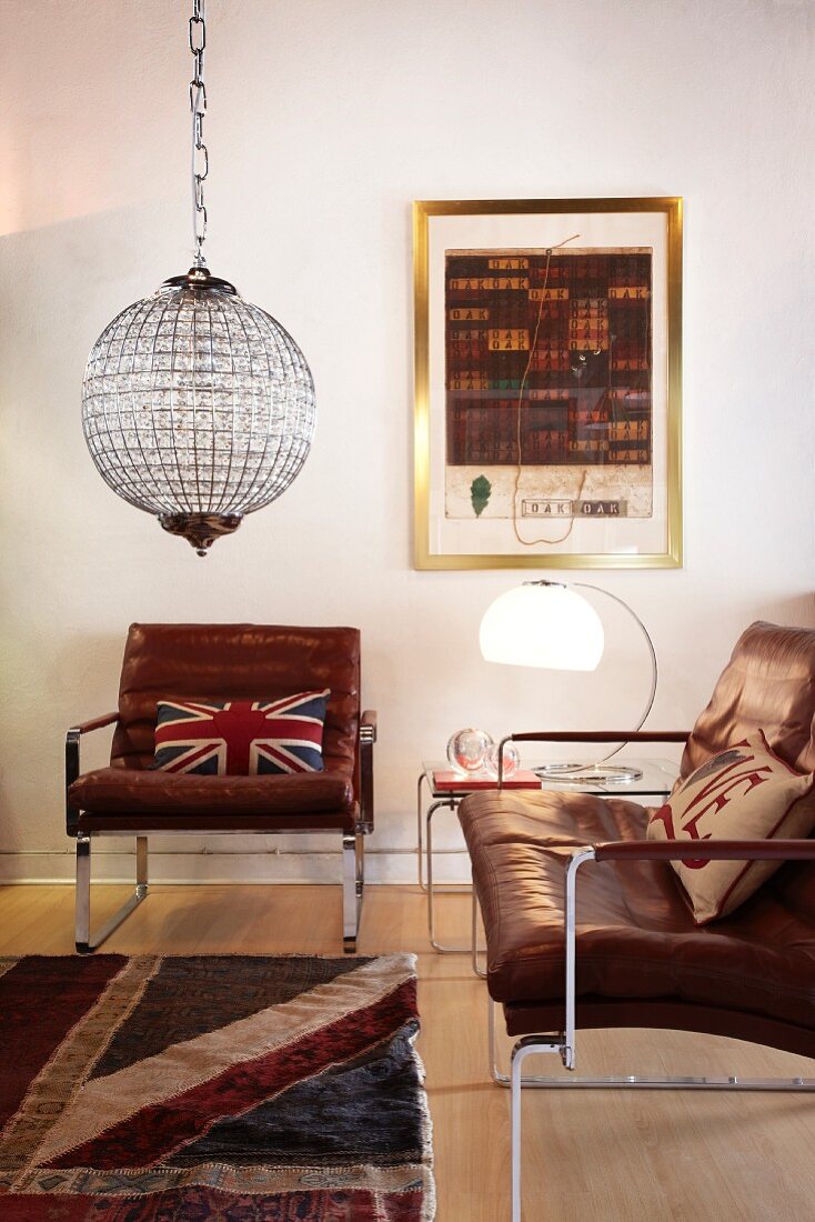 Vintage leather armchair and couch, both with stainless steel frames, and spherical glass light fitting in living room