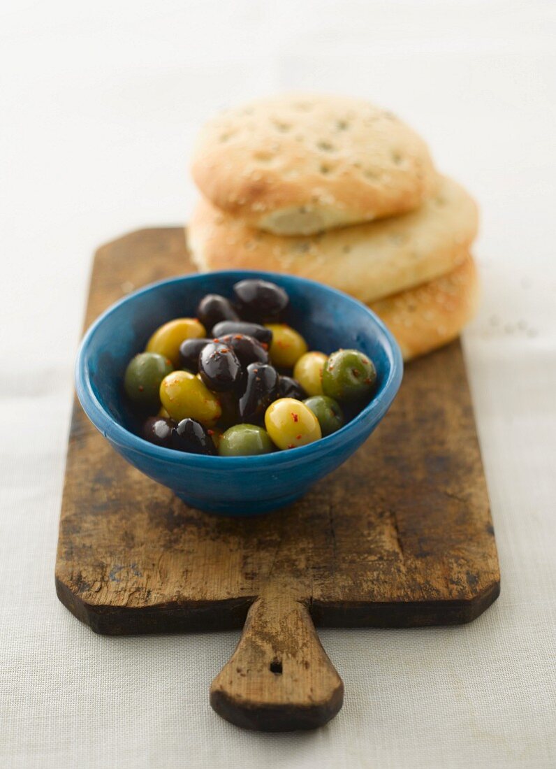 Olives and pita breads on a chopping board