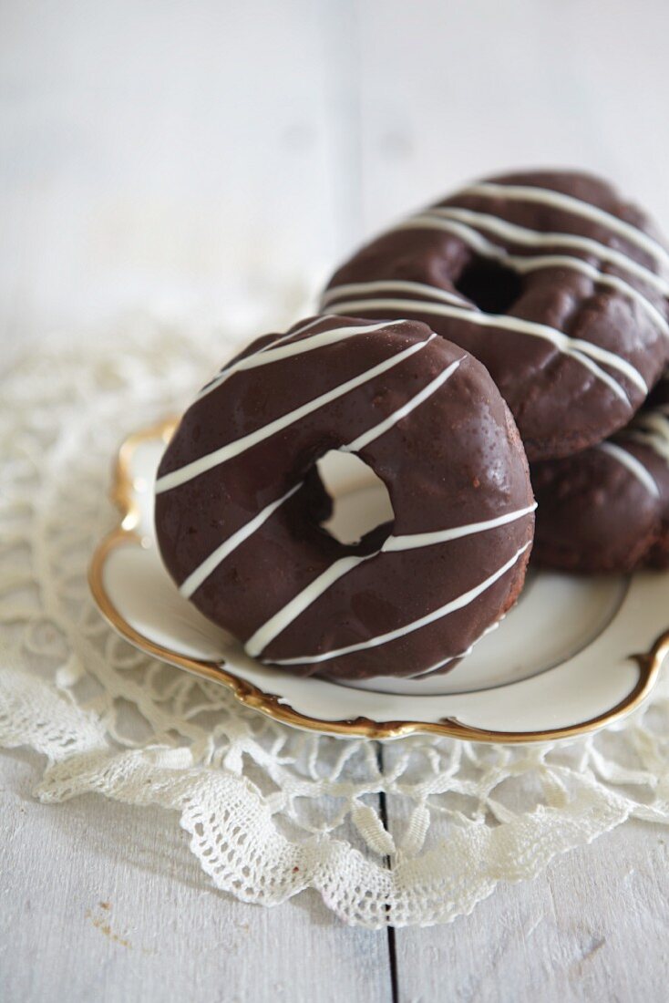 Ring doughnuts dipped in chocolate on a gold-edged plate