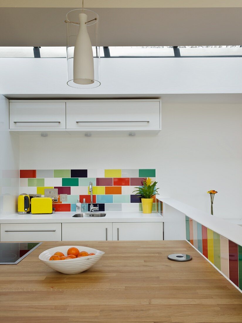 Küchentheke mit Holzarbeitsplatte in offener Küche mit bunten Wandfliesen