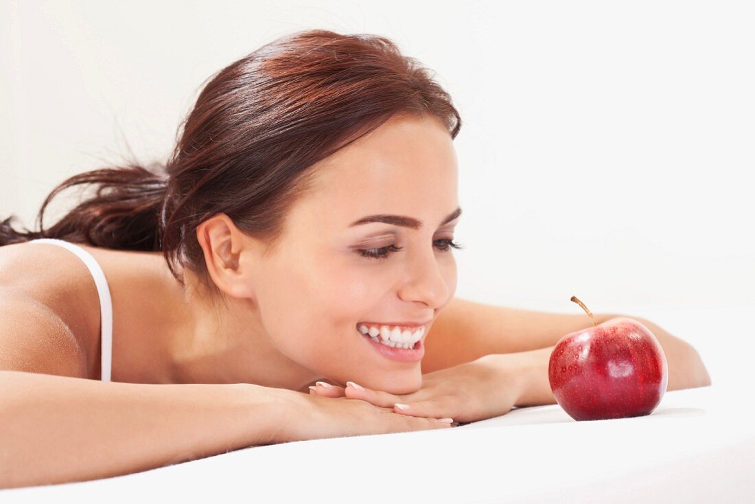 A woman looking at a red apple