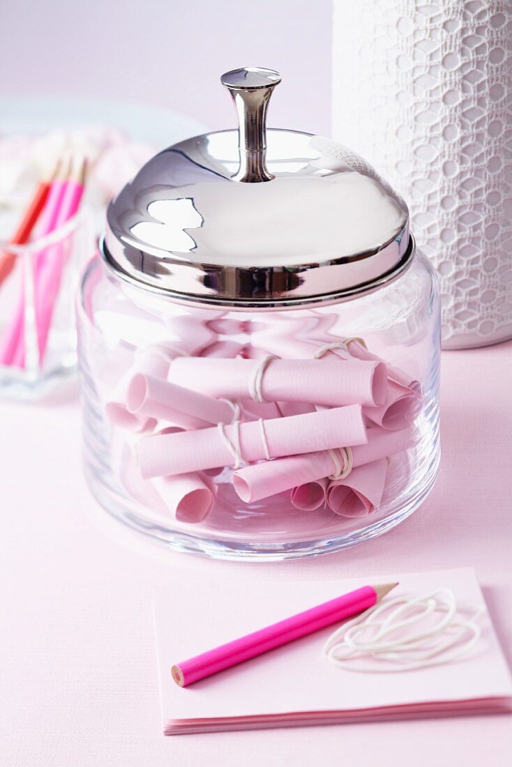 Glass container with rolled pieces of paper for wedding messages