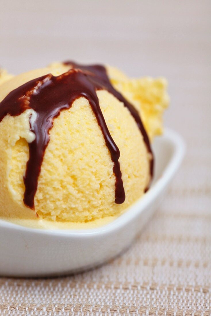 Home-made mango ice cream with chocolate sauce in a bowl