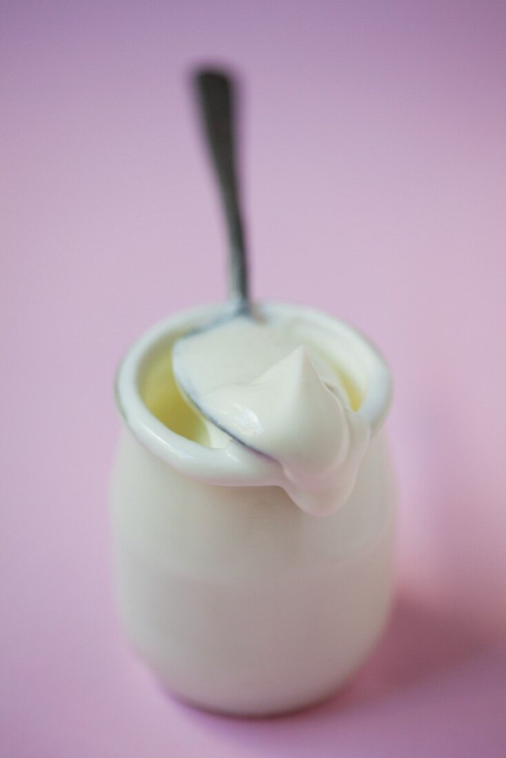 A jar of yoghurt with a spoon