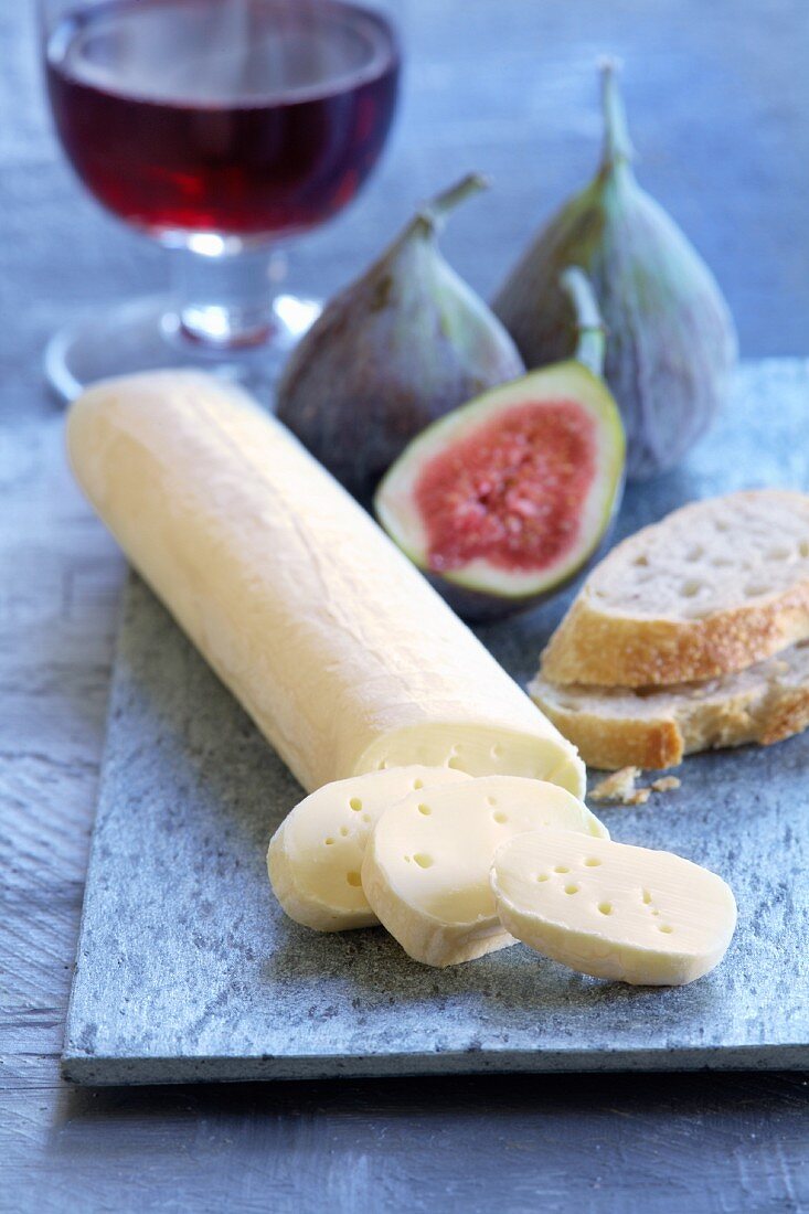 A log of soft cheese with bread and figs
