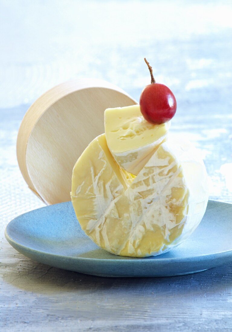 A Camembert on its side with a grape on top