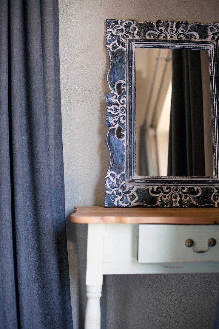 Mirror with ornate metal frame on rustic console table