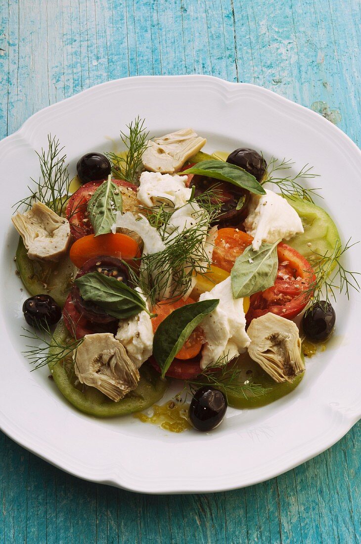 Tomato salad with mozzarella, artichokes, olives and herbs