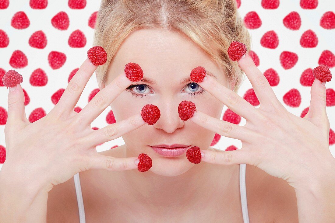 A blonde woman with raspberries on her fingertips
