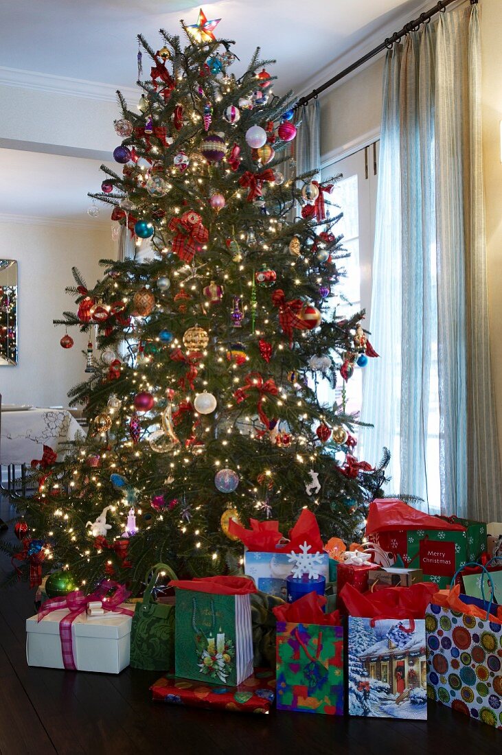 Viele Geschenkpäckchen unter einem prächtig geschmückten Weihnachtsbaum