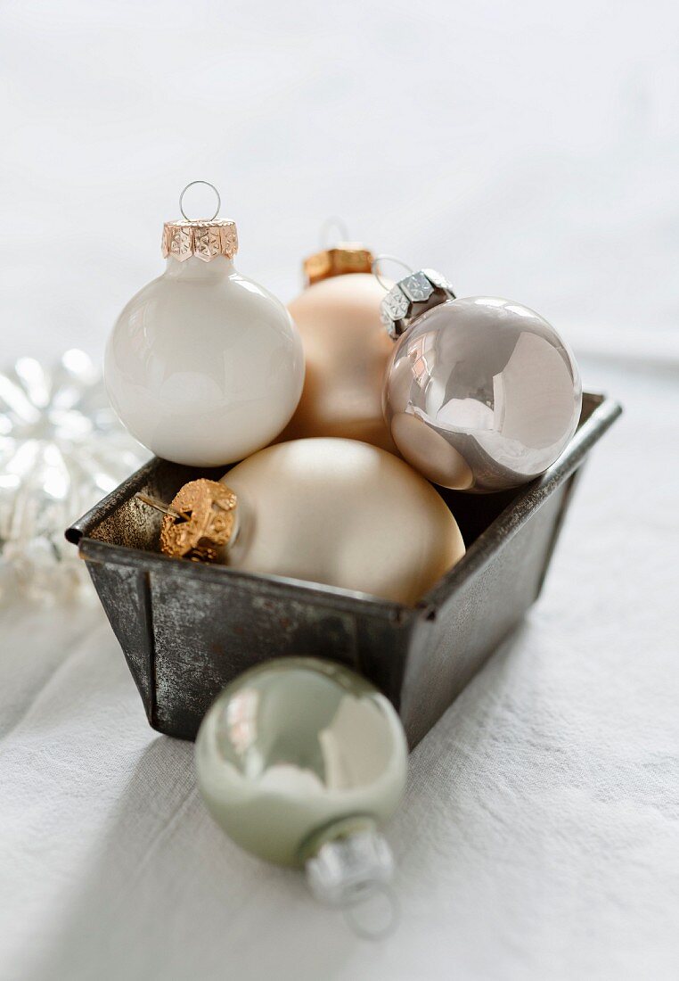 White, gold and silver Christmas tree baubles in a loaf tin