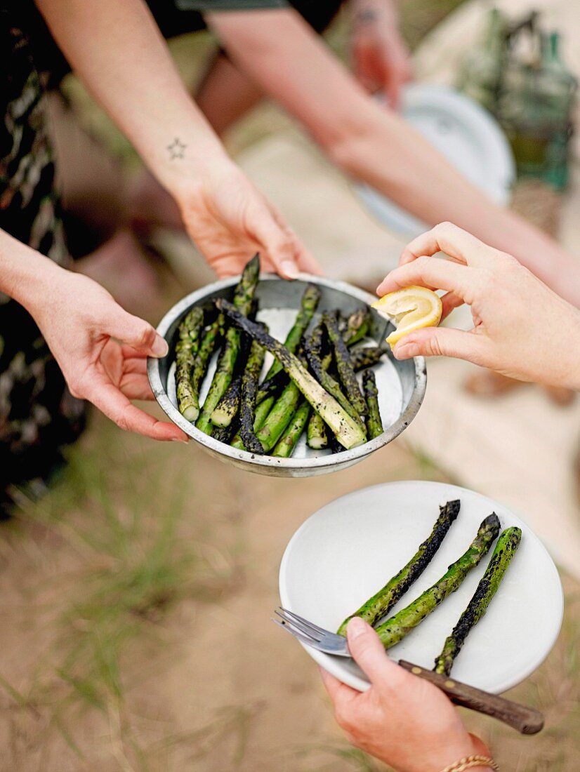 Leute essen gegrillten Spargel beim Strandpicknick