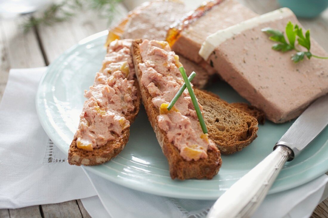 Toasted slices of bread spread with various types of pâté