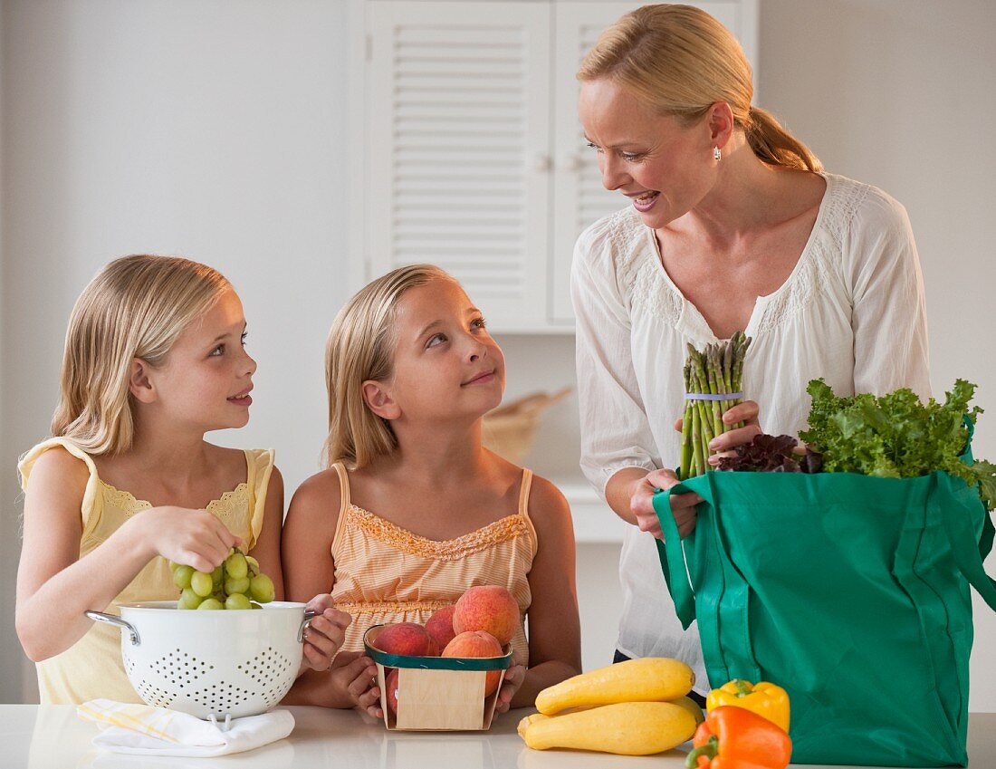 Mother with children (4-5) in kitchen, (focus on background)