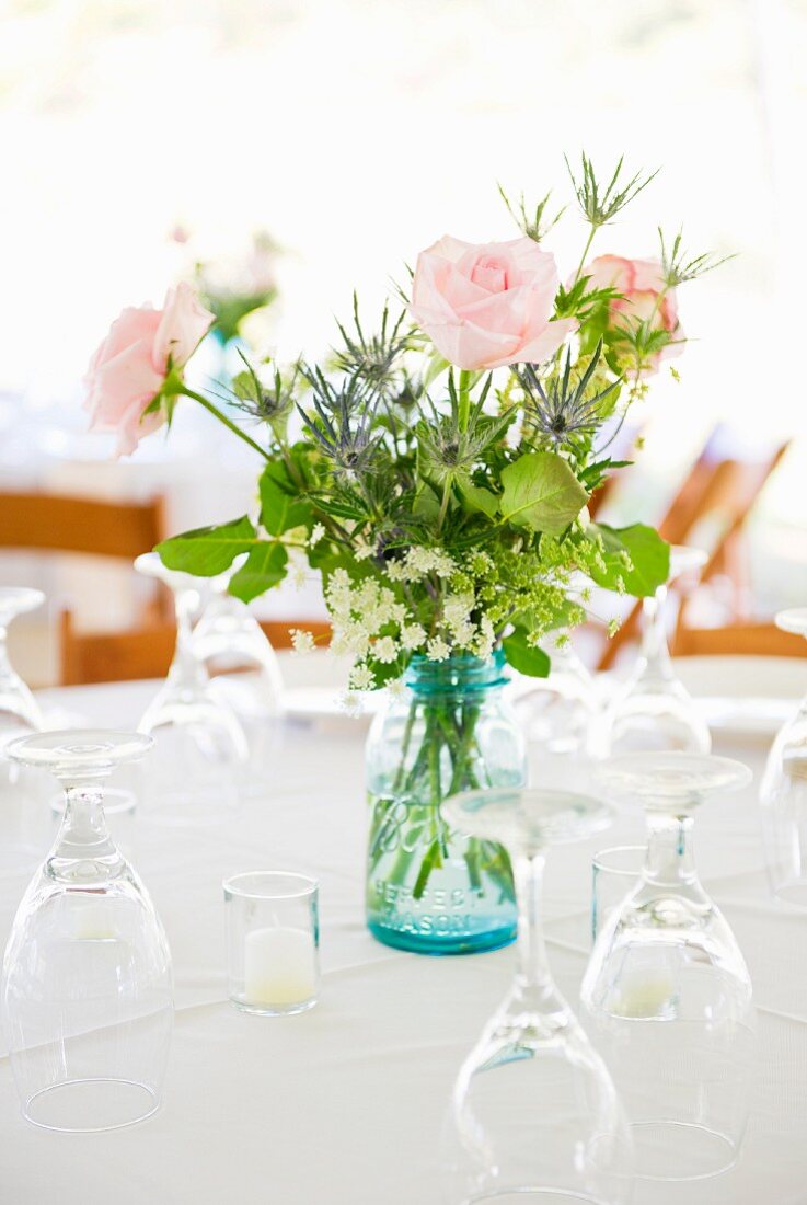 Rosen in einer Vase und Gläser auf gedecktem Tisch