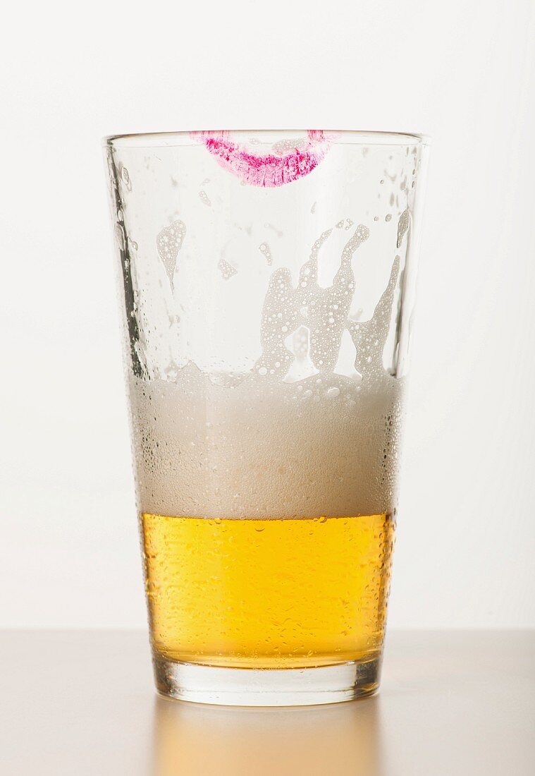 Studio shot of beer glass with lipstick mark on edge
