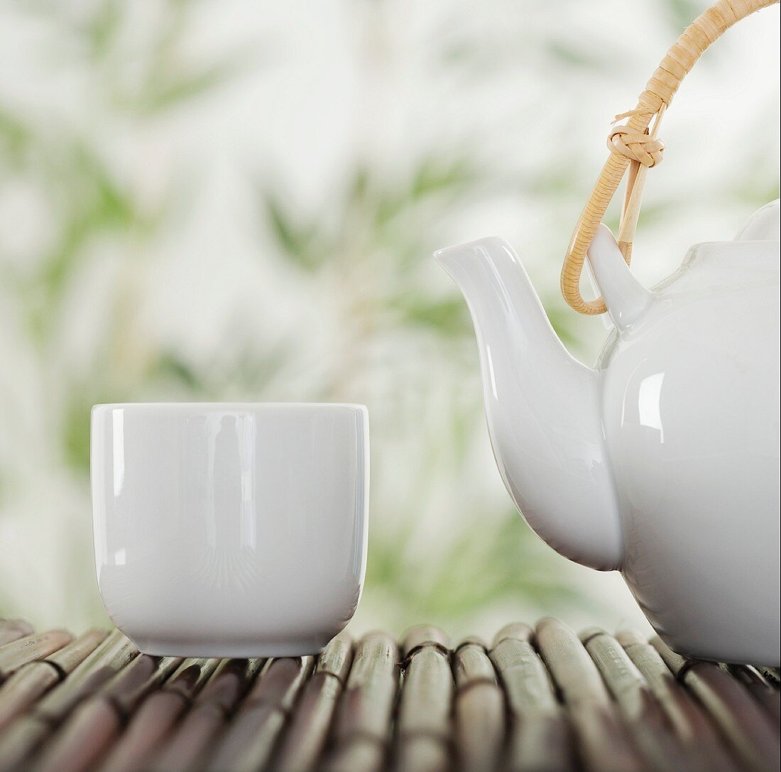 Teekanne und Tasse auf Bambus