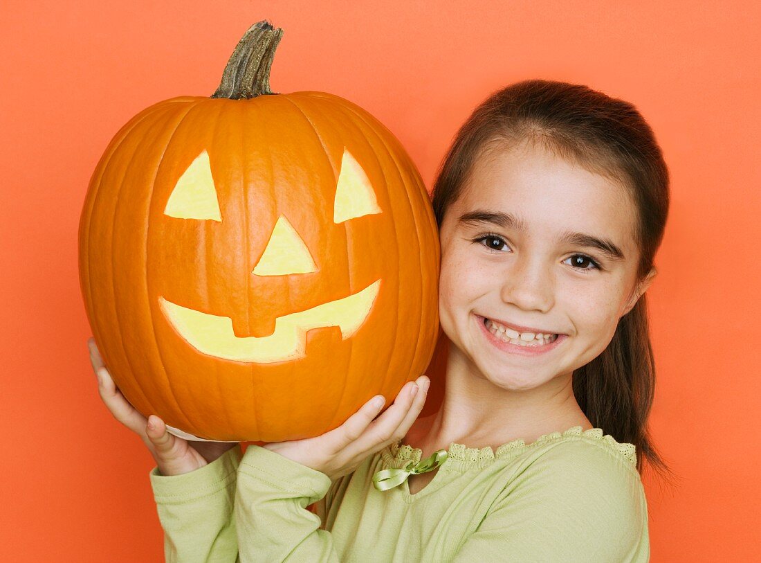 Smiling girl holding a jack o lantern