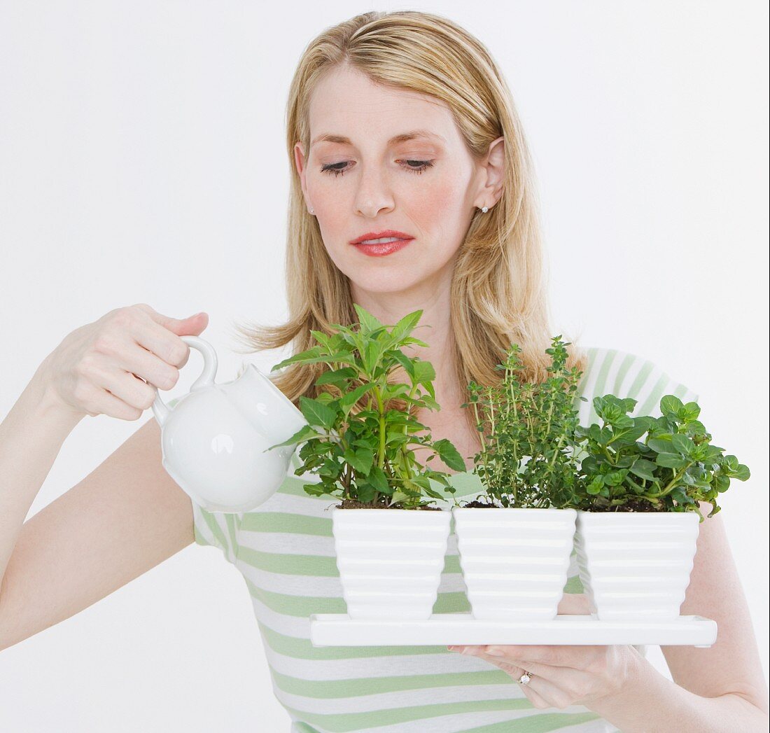 Woman watering herbs in pots