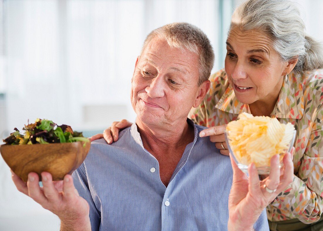 An older couple choosing between salad and crisps