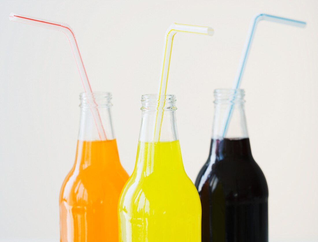Drei Glasflaschen mit Limonade und Strohhalmen