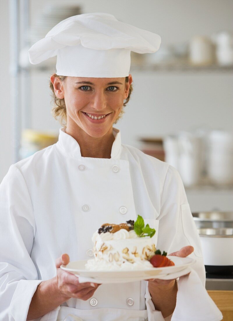 Female chef holding plate of dessert