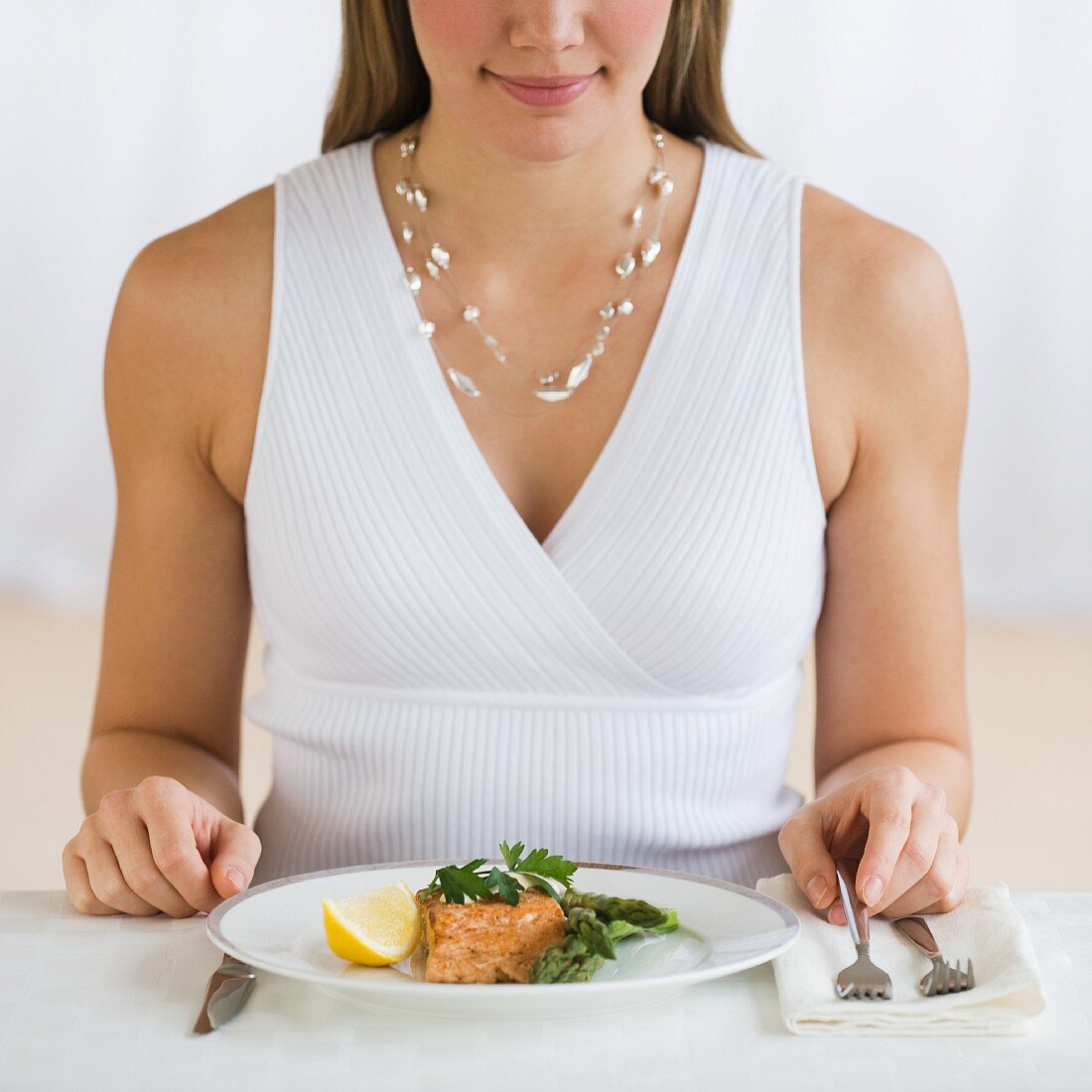 Frau sitzt am Tisch mit Lachsgericht