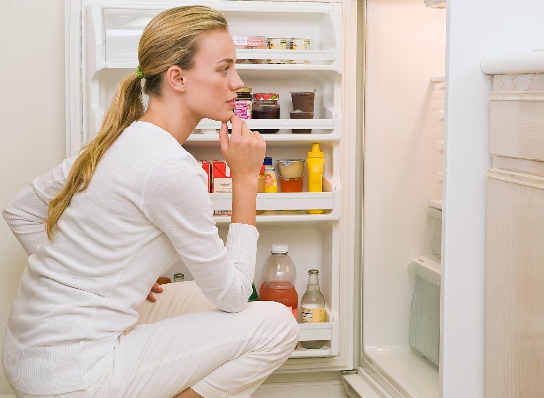 Frau schaut in den Kühlschrank
