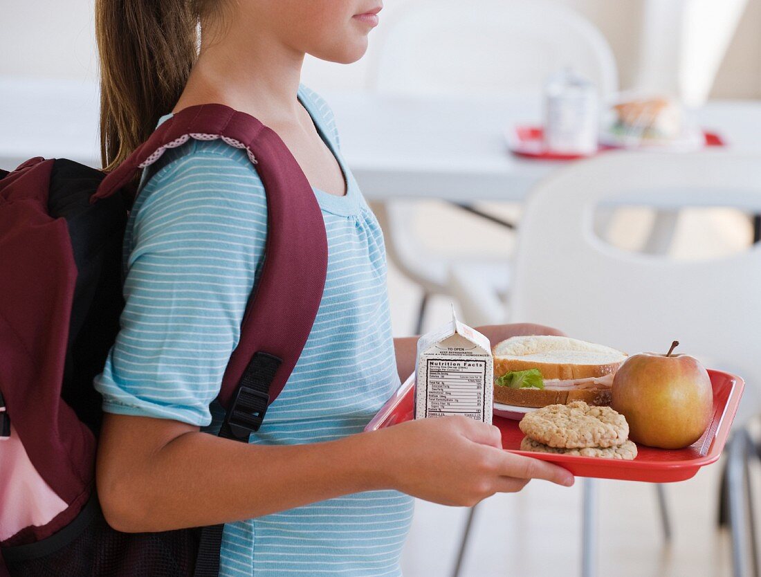 Mädchen trägt Tablett mit Mittagessen in der Schule