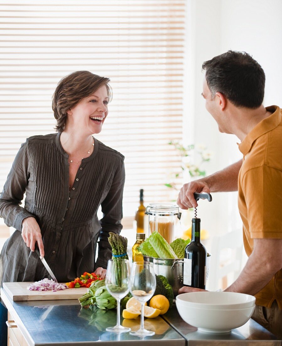 Couple cooking together, woman holding fresh basil