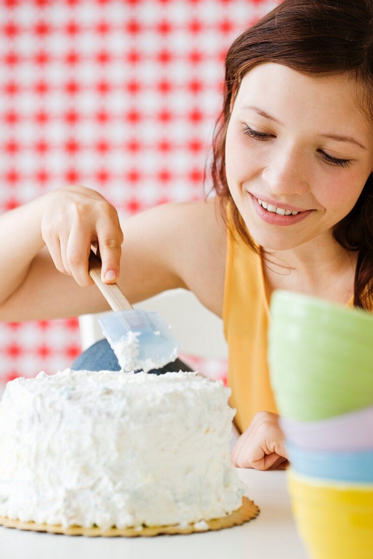 Teenage girl frosting cake