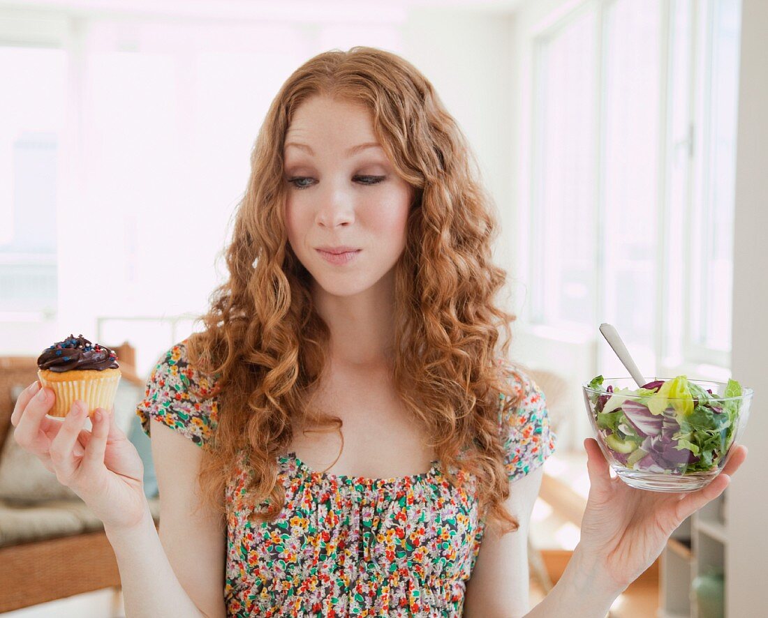 Frau mit Cupcake und mit Salat