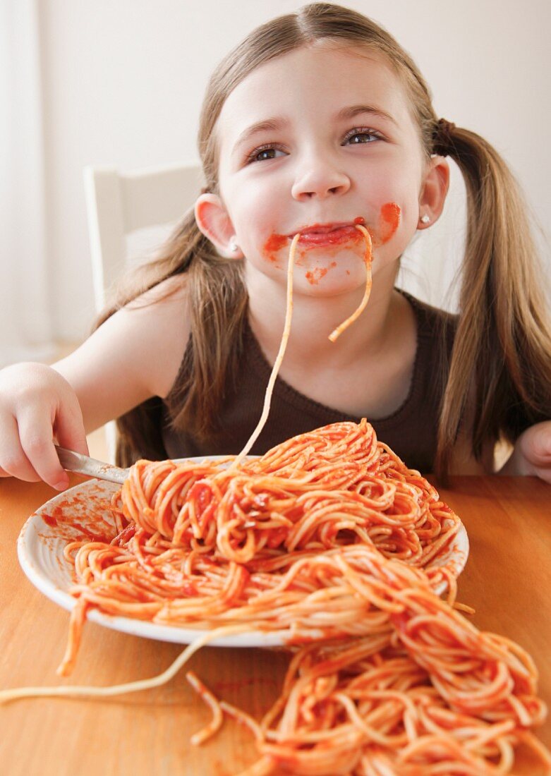 Mädchen isst Spaghetti mit Tomatensauce