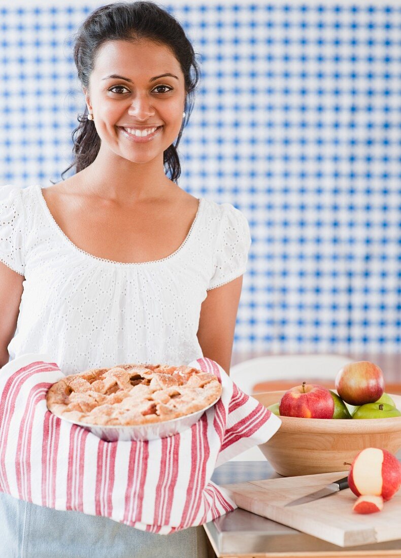 Junge Frau hält einen frisch gebackenen Apfelkuchen