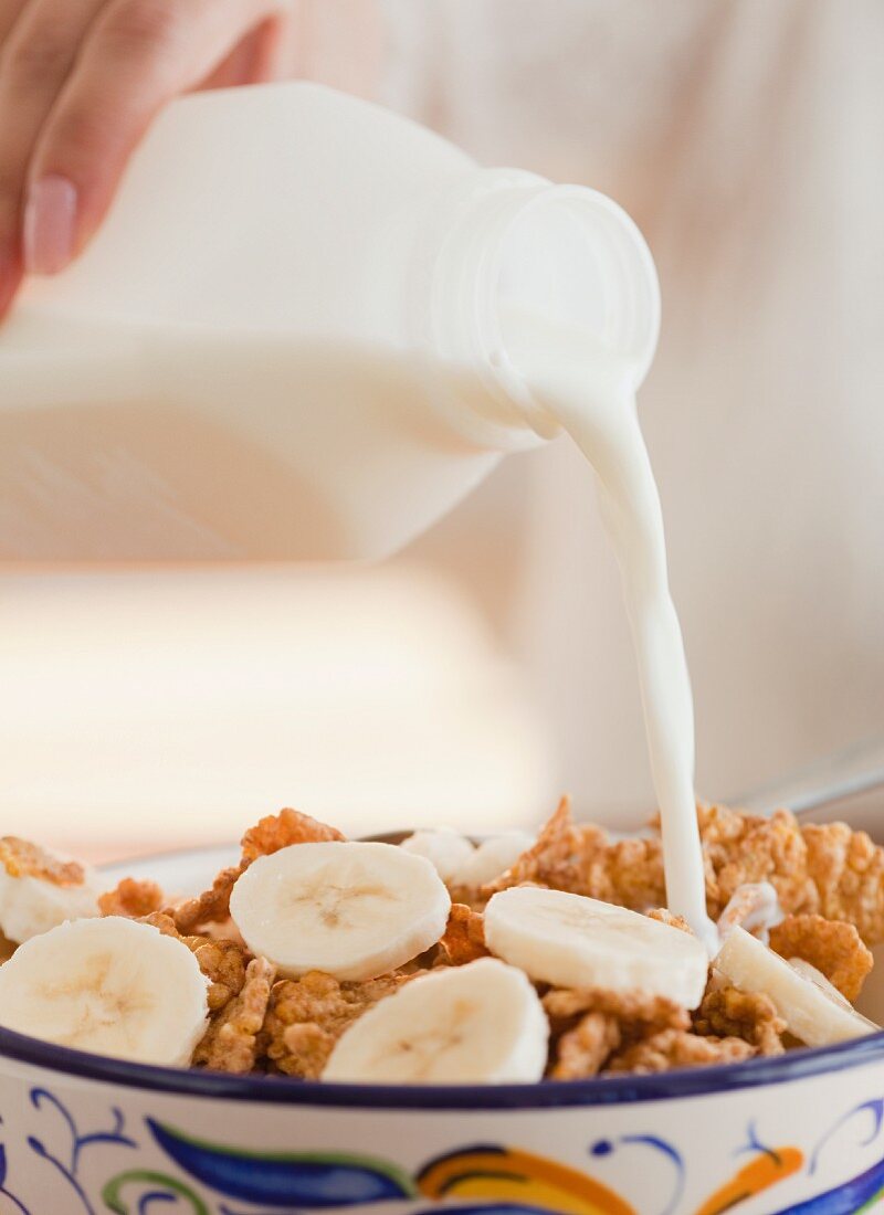 Milch über Cornflakes mit Banane gießen