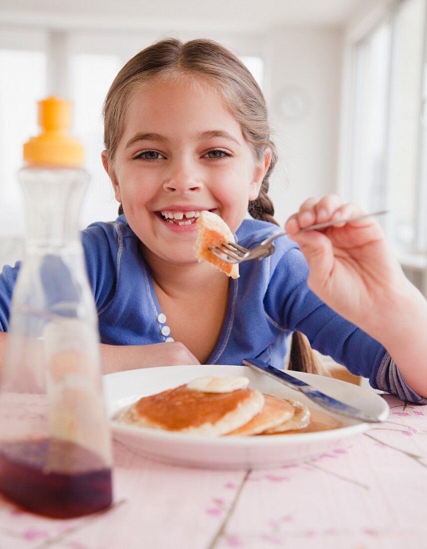 Mädchen isst Pancake mit Ahornsirup
