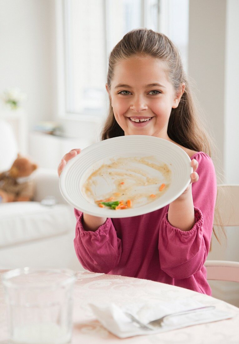 Mädchen zeigt leer gegessenen Teller