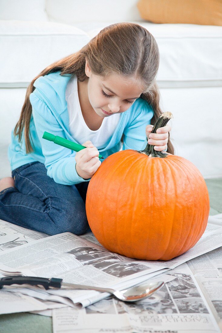 Young girl drawing on pumpkin