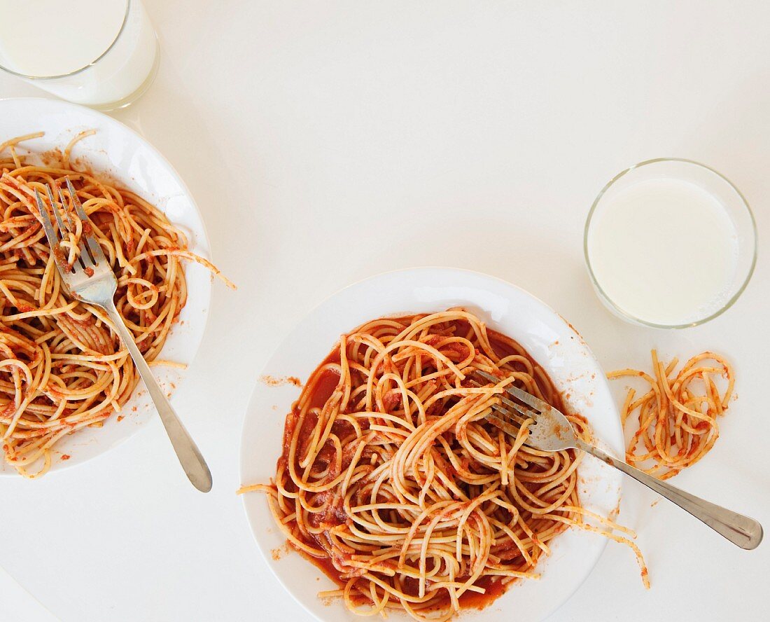 Zwei Teller Spaghetti mit Tomatensauce und Milchgläser