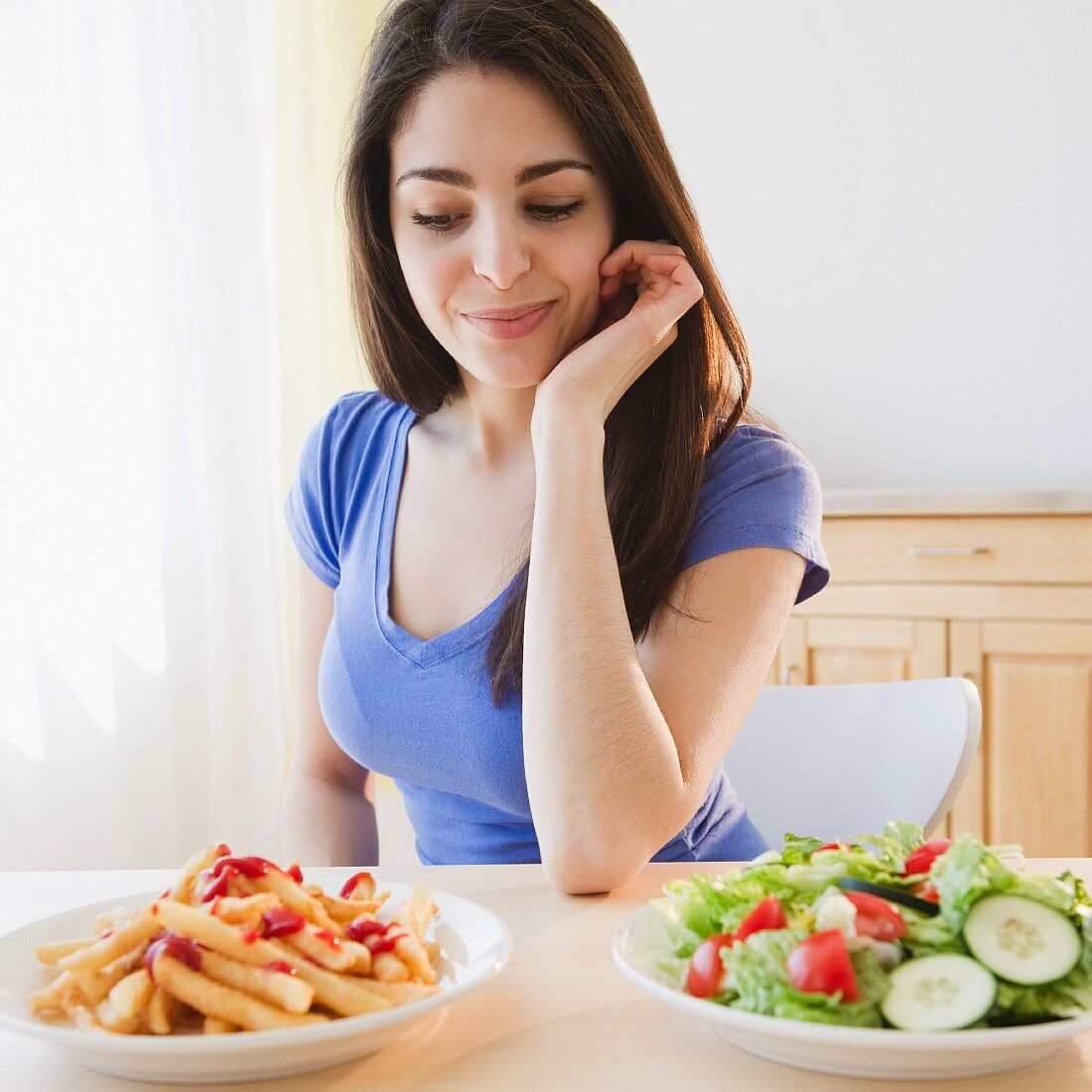 Junge Frau vor der Entscheidung: Pommes mit Ketchup oder Salat