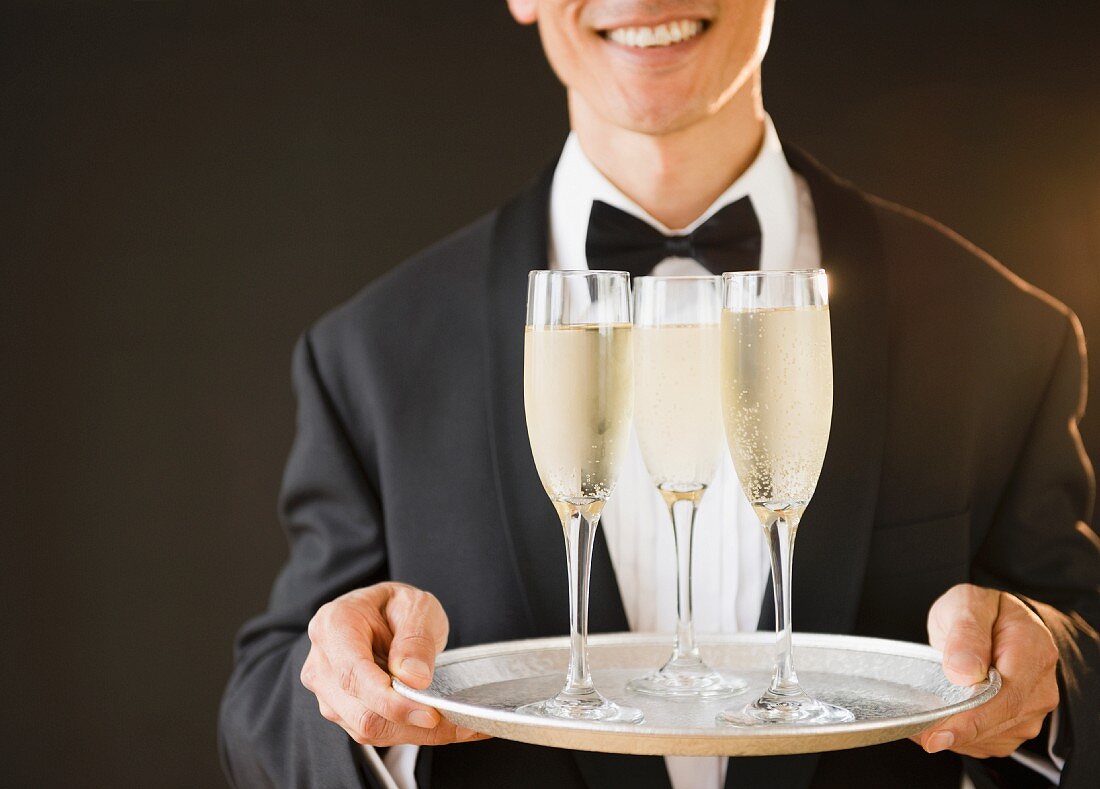 A waiter holding a tray of champagne glasses