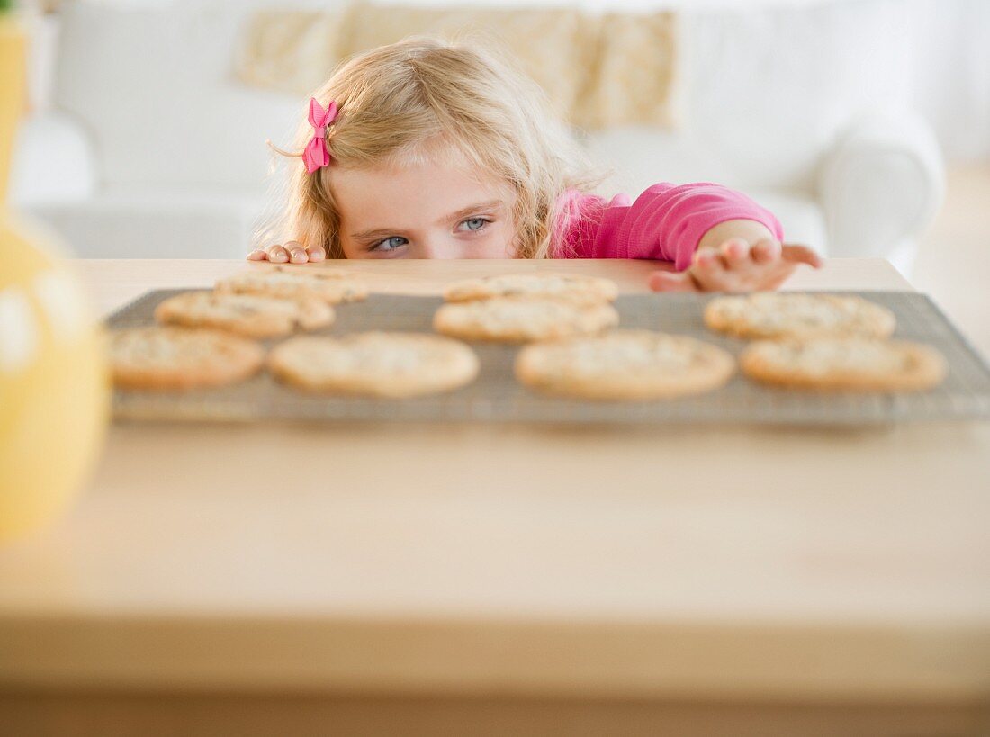 Girl (4-5) reaching for cookies
