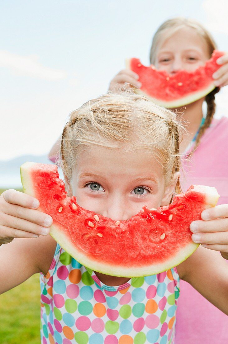 Girls (6-7, 8-9) eating watermelon