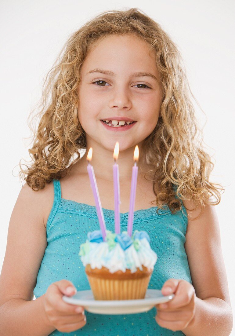 Mädchen hält Cupcake mit Kerzen