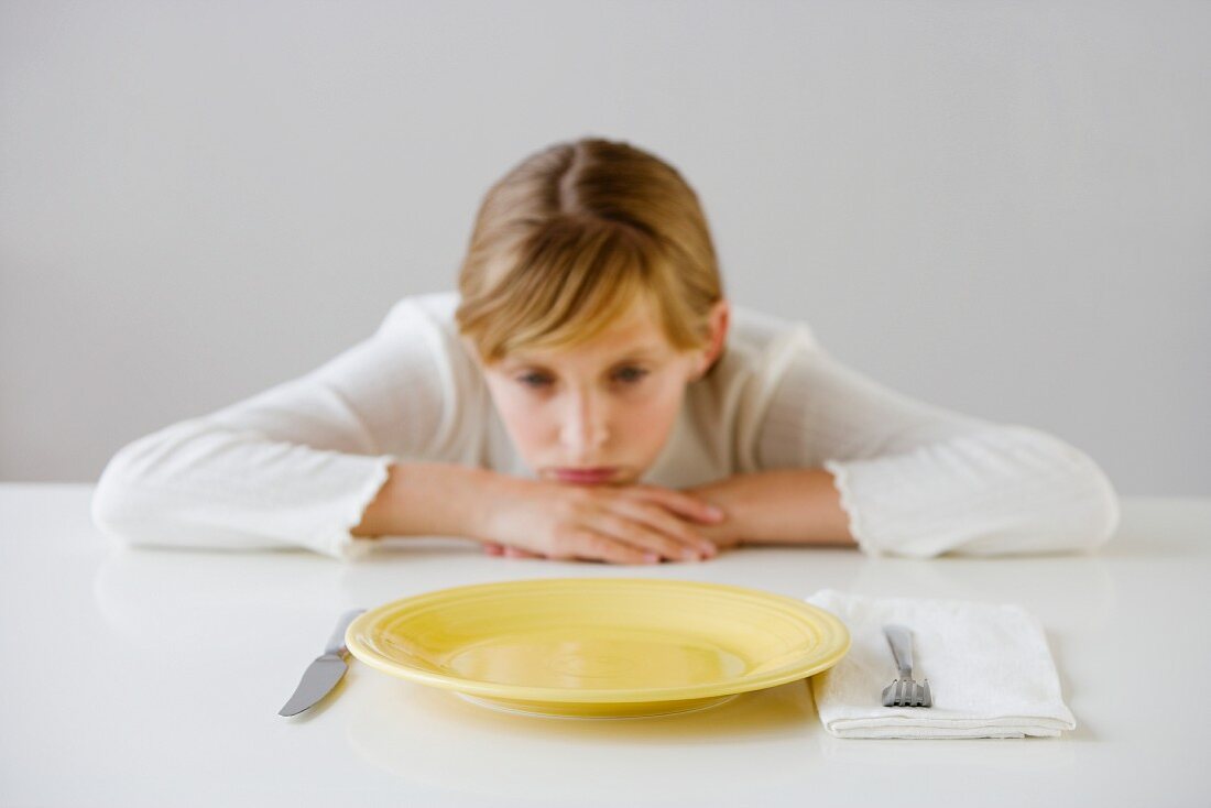 Teenaged girl looking at empty plate