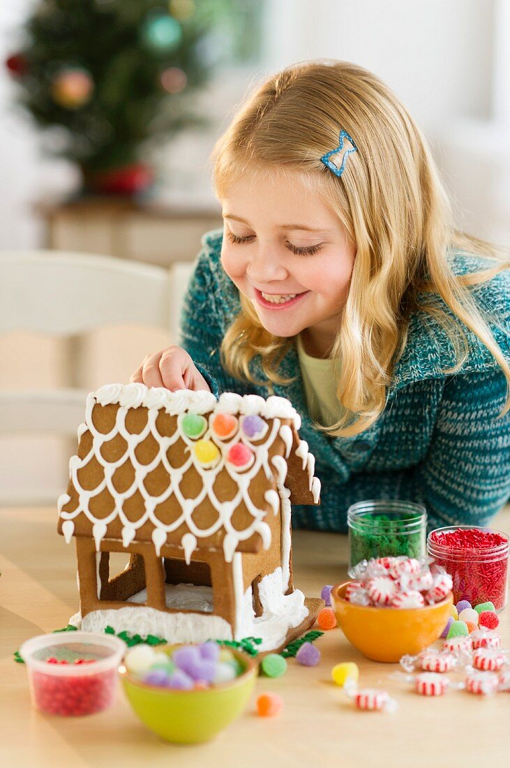 Mädchen verziert ein Lebkuchenhaus